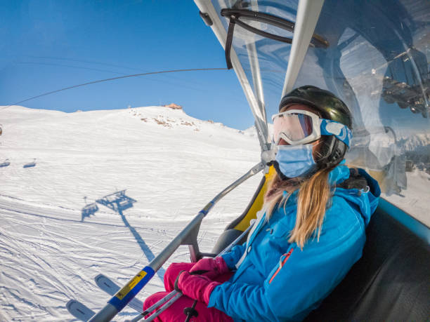 Woman on ski lift, Covid-19 She sits on chair lift and wears face mask graubunden canton stock pictures, royalty-free photos & images