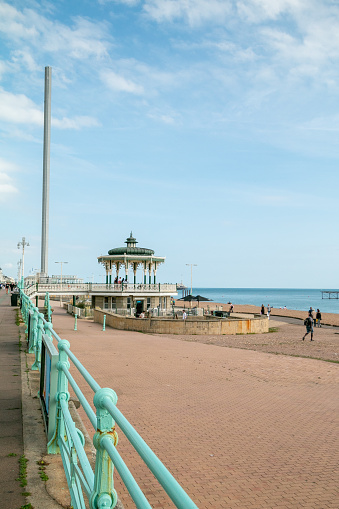 Bandstand on Brighton Beach in East Sussex, England, with the i360 Tower on the left and people on Brighton Beach on the right