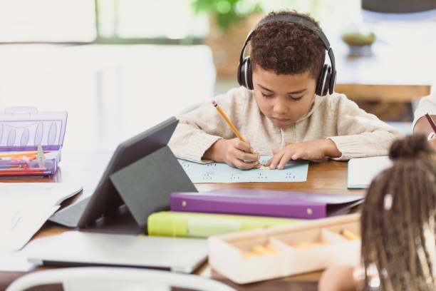istock Boy listens to music while filling out worksheet for school 1292600866