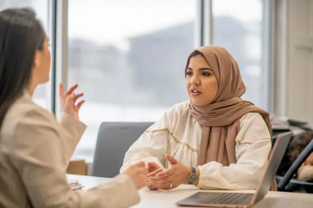 A female Muslim woman is speaking to her family doctor at the office to discuss her family's health history.