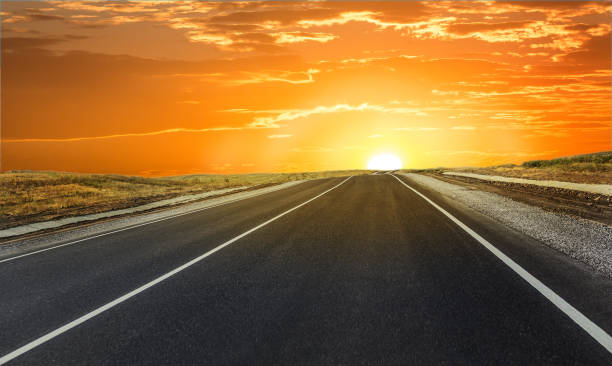 istock Empty suburban highway at sunset illuminated by the sun 1292603205