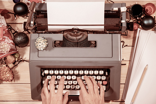 Vintage atmosphere. Typing a letter or a manuscript on an old typewriter during Christmas time. Pine cones and decorations all around.