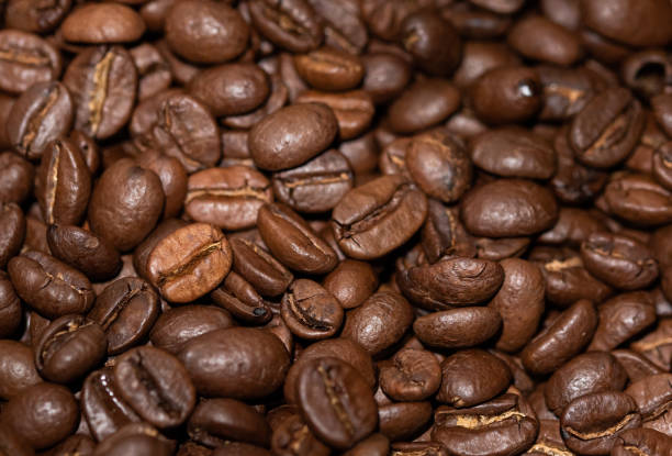 granos de café tostados de primer plano, fondo marrón - kona coffee fotografías e imágenes de stock