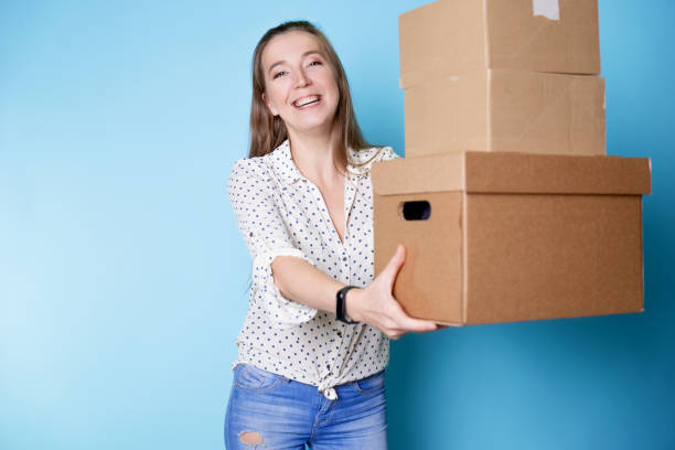 istock Accept a parcel, happy young woman holding a stack of cardboard boxes, 1292605498