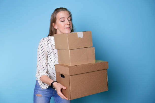 istock Accept a parcel, happy young woman holding a stack of cardboard boxes, 1292605503