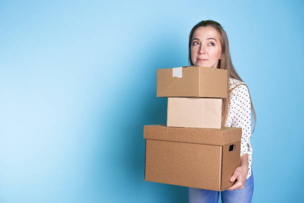 istock Accept a parcel, happy young woman holding a stack of cardboard boxes, 1292605506
