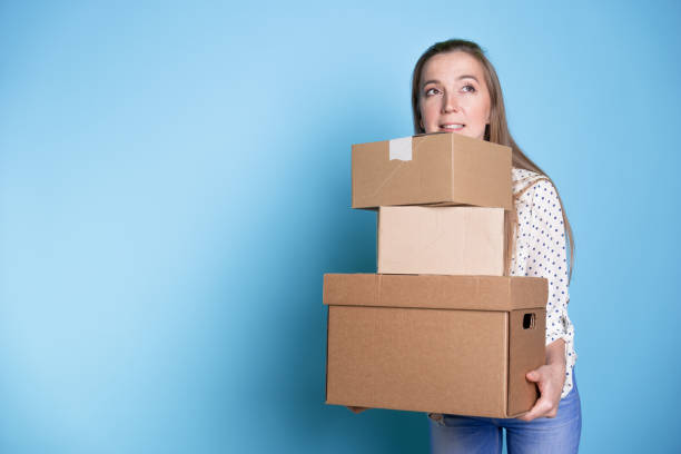 istock Accept a parcel, happy young woman holding a stack of cardboard boxes, 1292605510