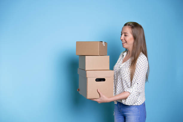 istock Accept a parcel, happy young woman holding a stack of cardboard boxes, 1292605518