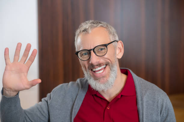 istock Smiling grey-haired bearded man waving his hand 1292605822