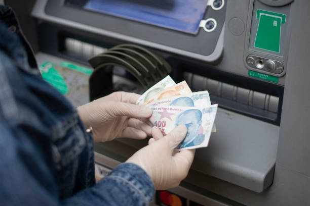 Woman who protects her hands with protective gloves withdraws - deposits money from ATM (bank) (COVID-19-Korona virus) stock photo