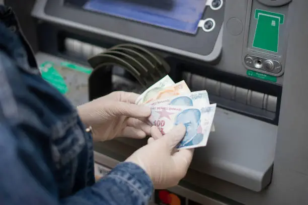 Woman who protects her hands with protective gloves withdraws - deposits money from ATM (bank) (COVID-19-Korona virus)