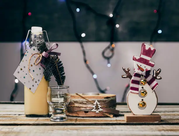 Photo of Homemade alcohol egg liquere with jar, candle and snowman decoration on wood table