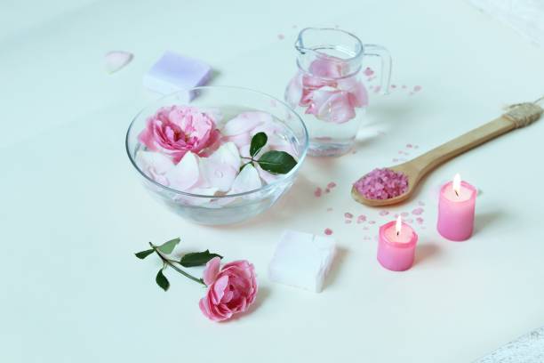 istock Fresh pink roses, water, petals, candles on a light background 1292612465