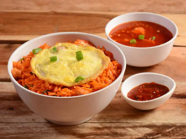 Triple Schezwan Fried Rice is a lip smacking complete meal combination of Rice, chicken,egg and crispy fried noodles served with spicy and fragrant schezwan gravy, Indian cuisine, selective focus