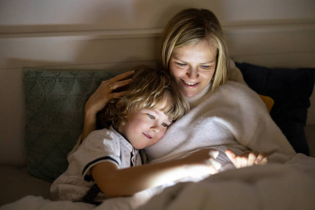 istock Mother and son using digital tablet together at night in bed 1292617197