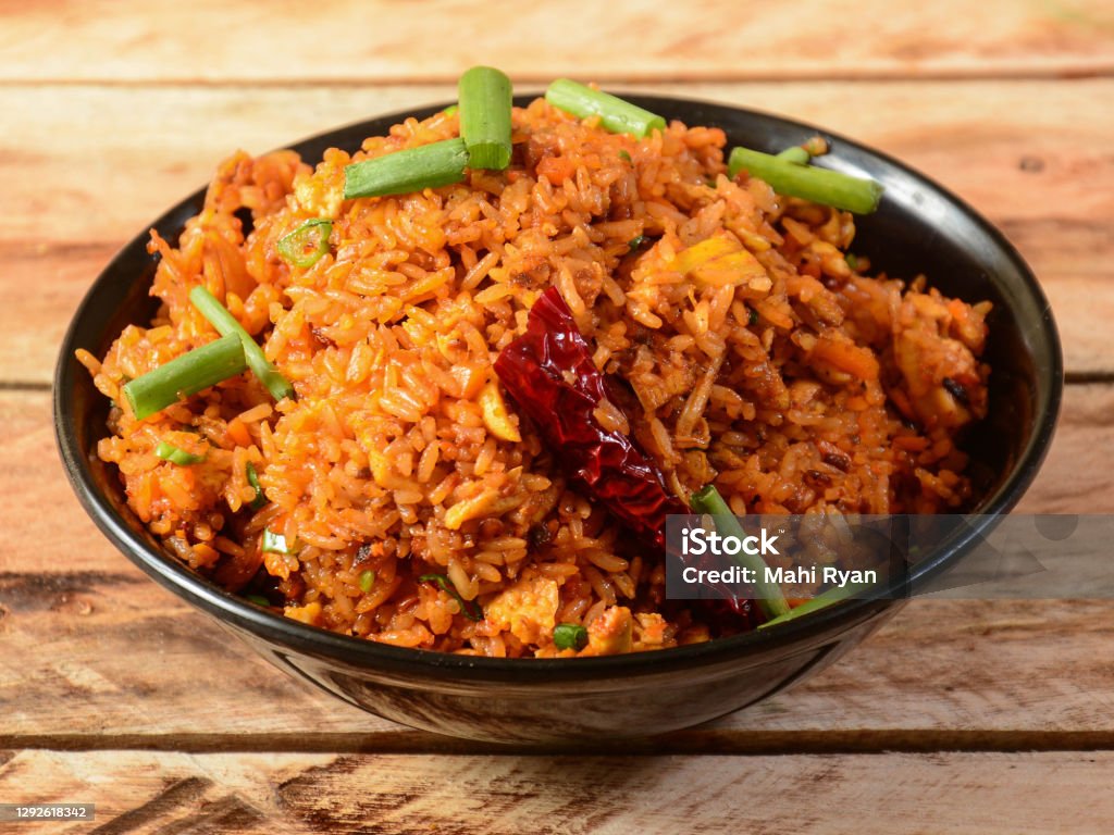 Tasty veg schezwan fried rice served in bowl over a rustic wooden background, Indian cuisine, selective focus Fried Rice Stock Photo