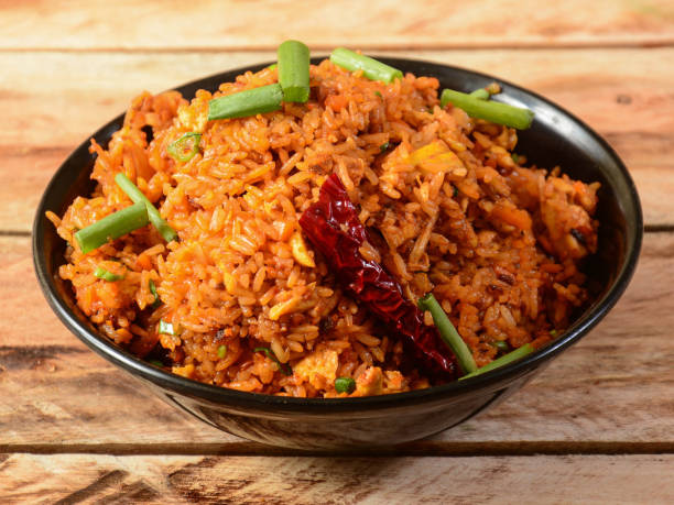 Tasty veg schezwan fried rice served in bowl over a rustic wooden background, Indian cuisine, selective focus Tasty veg schezwan fried rice served in bowl over a rustic wooden background, Indian cuisine, selective focus fried rice stock pictures, royalty-free photos & images