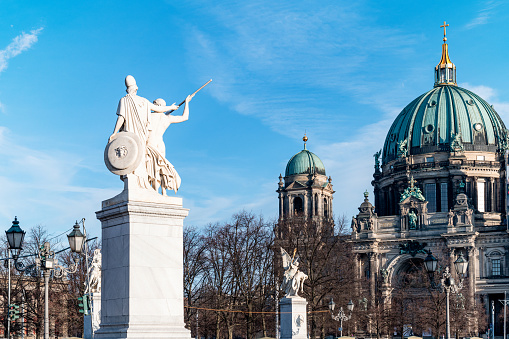 historic statues in in front of cathedral in Berlin under blue december sky