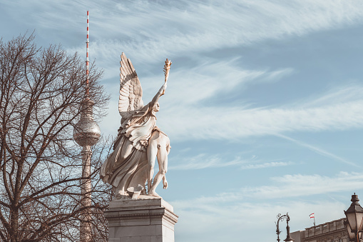 historic statue in in front of TV-Tower in Berlin under blue december sky