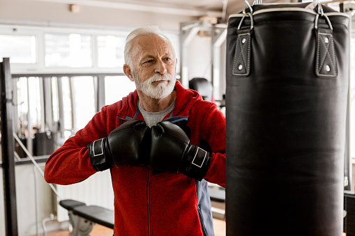 Senior in gym training boxing