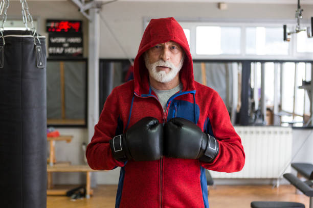 Senior man training boxing in gym looking at camera