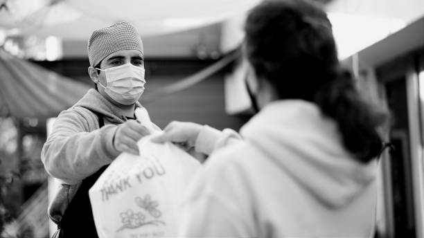 Woman picking up her meal at a curbside pickup, both wearing protective face masks