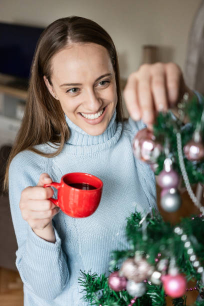 istock Young woman decorating Christmas tree 1292622122