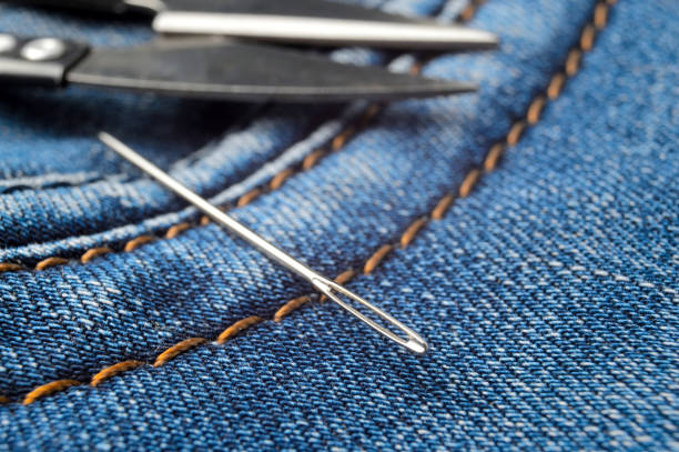istock sewing needle and scissors lie on blue jeans. close-up. 1292622457