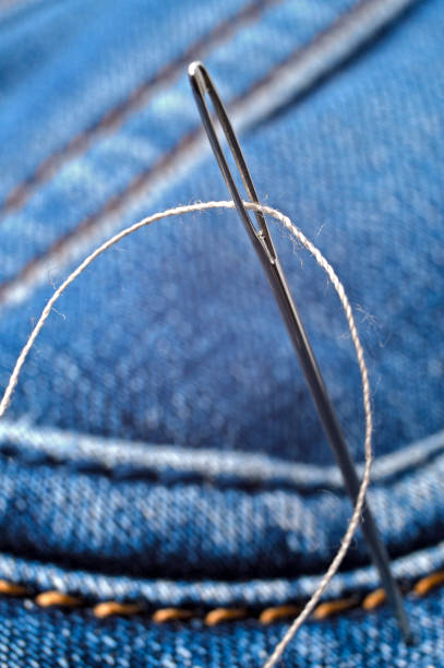 istock Close-up shot of needle with thread on jeans material. Close-up. 1292623062