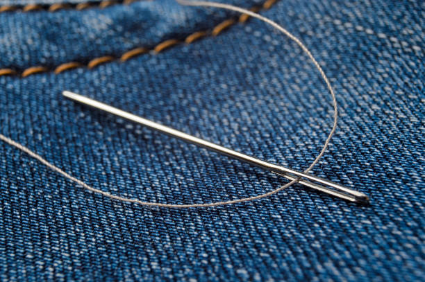 istock Close-up shot of needle with thread on jeans material. Close-up. 1292623098