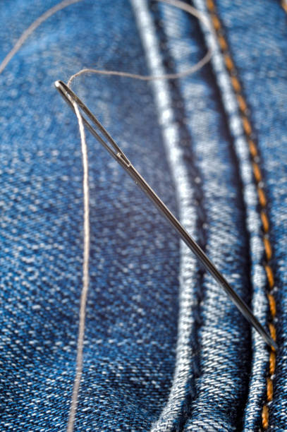 istock Close-up shot of needle with thread on jeans material. Close-up. 1292623197