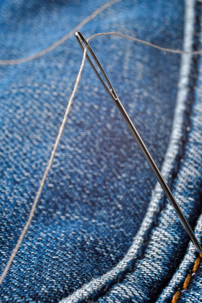 istock Close-up shot of needle with thread on jeans material. Close-up. 1292623358