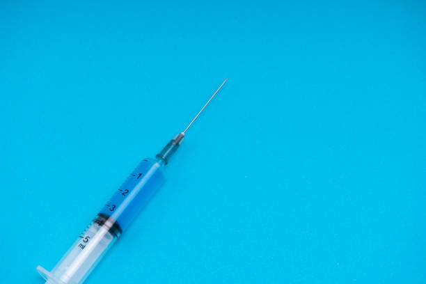istock Medical syringe with vaccine on a blue background 1292625800