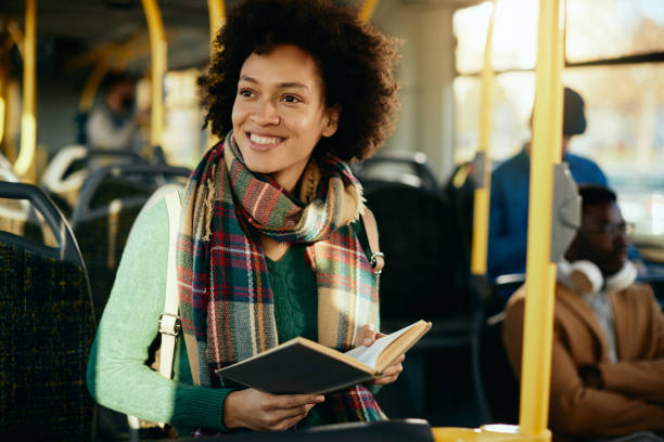 istock Happy African American woman reading a book while commuting by bus. 1292625983