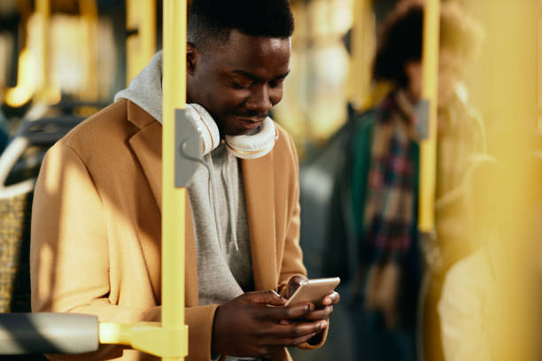 istock Smiling African American man text messaging on cell phone while traveling by bus. 1292626163