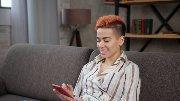 istock Happy woman surfs internet with smartphone sitting on sofa 1292626233
