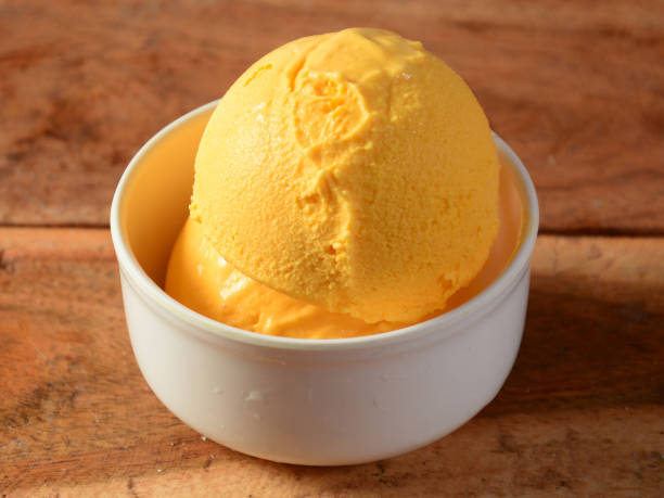 istock Mango ice cream scoops served in a white bowl over a rustic wooden table, selective focus 1292626744