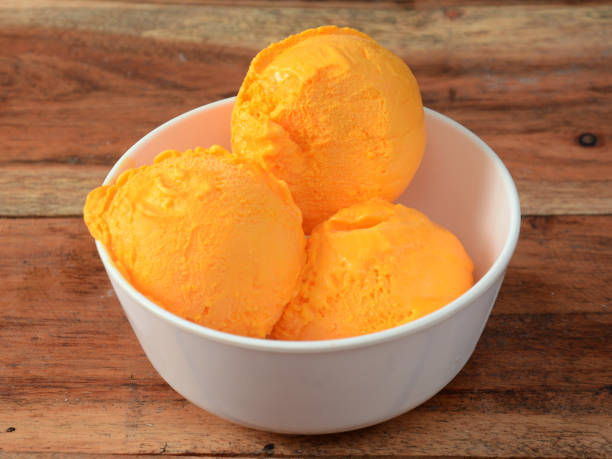 istock Mango ice cream scoops served in a white bowl over a rustic wooden table, selective focus 1292626785