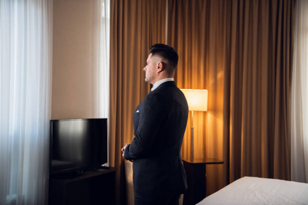 istock A young man in a suit standing in a hotel room, looking into the 1292626825