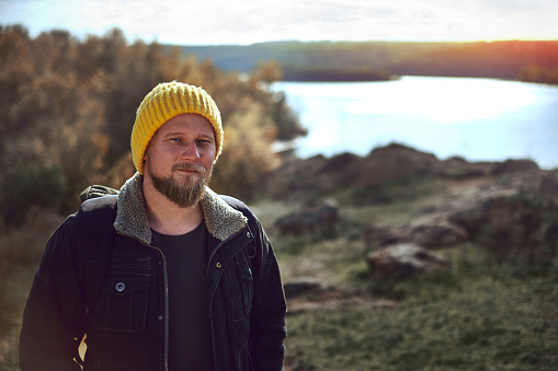 Portrait of a traveler with a backpack on his back against the background of autumn nature