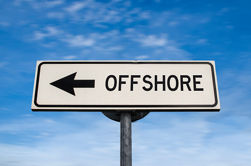 Outsourcing work force. White sign with arrow with offshore word. Direction sign. Arrows on a pole pointing in one direction. IT offshoring concept.