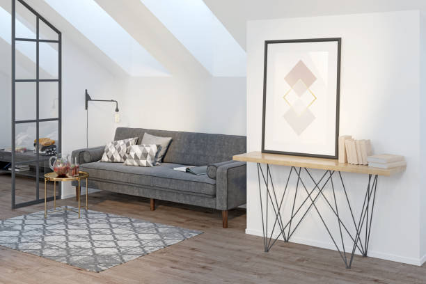 istock Light attic with a vertical poster and books on a sideboard, a gray sofa with pillows, a coffee table with drinks, a glass partition, a carpet on a wooden floor, two windows on the roof. 1292627435