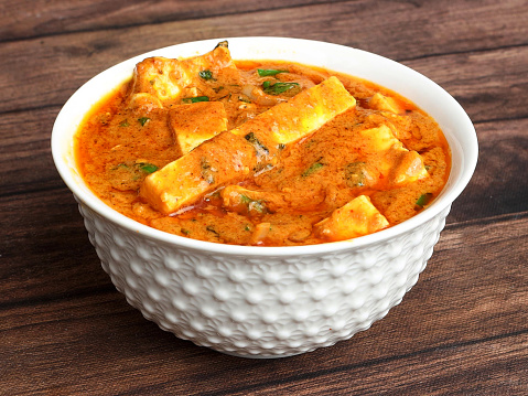 Paneer lababdar, is a famous indian dish, served over a rustic wooden background, selective focus