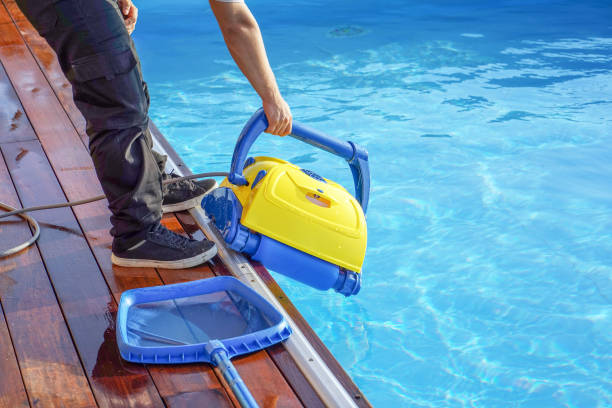 istock Hotel staff worker cleaning the pool. A pool cleaner holds a robot cleaner. 1292628453