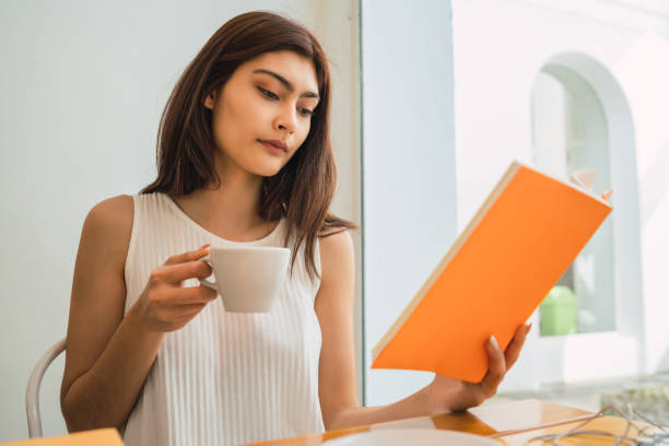 istock Young woman reading a book at coffee shop. 1292632002