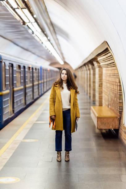 istock stylish woman in autumn clothes looking at train on underground platform, blurred background 1292632452