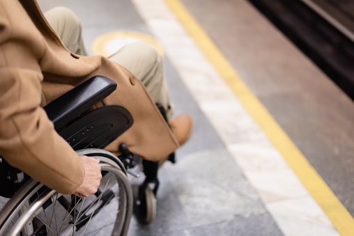 cropped view of blurred handicapped man in wheelchair on subway platform