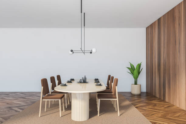 istock White wooden dining room with brown chairs and oval table, white wall 1292635451