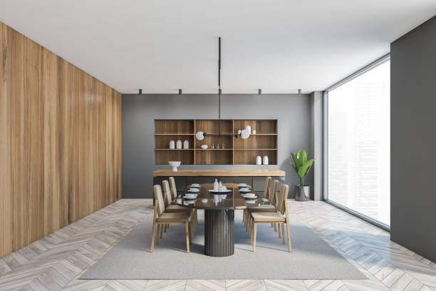 istock Grey wooden dining room with oval table with dishes and chairs, big window 1292635594