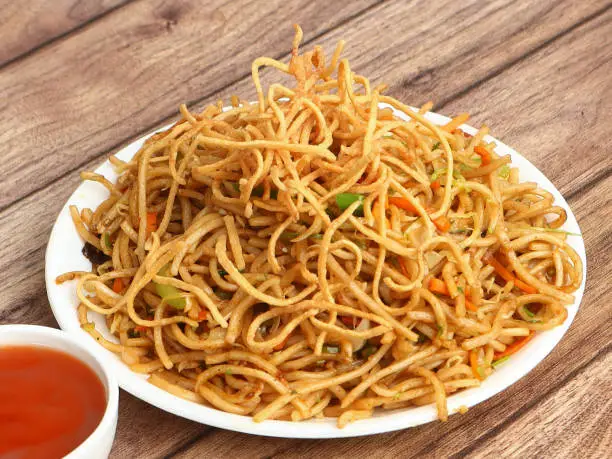 Photo of Veg Hakka Noodles a popular oriental dish made with noodles and vegetables, served over a rustic wooden background, selective focus